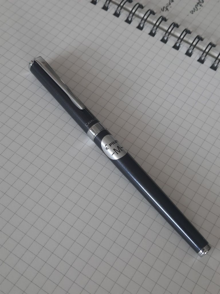 A Pilot Cavalier fountain pen placed on top of a grid-patterned notebook page.